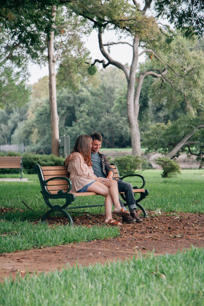 Image of a man and woman sitting together on a bench in a park.