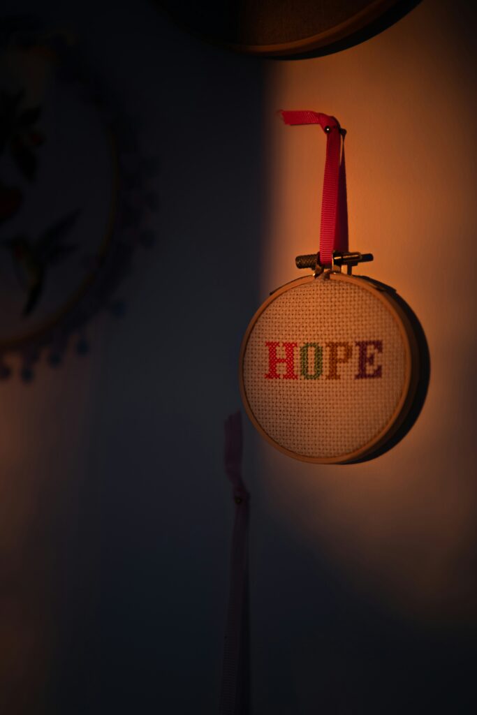 Image of a cross stich pattern hanging on the wall that says "Hope"